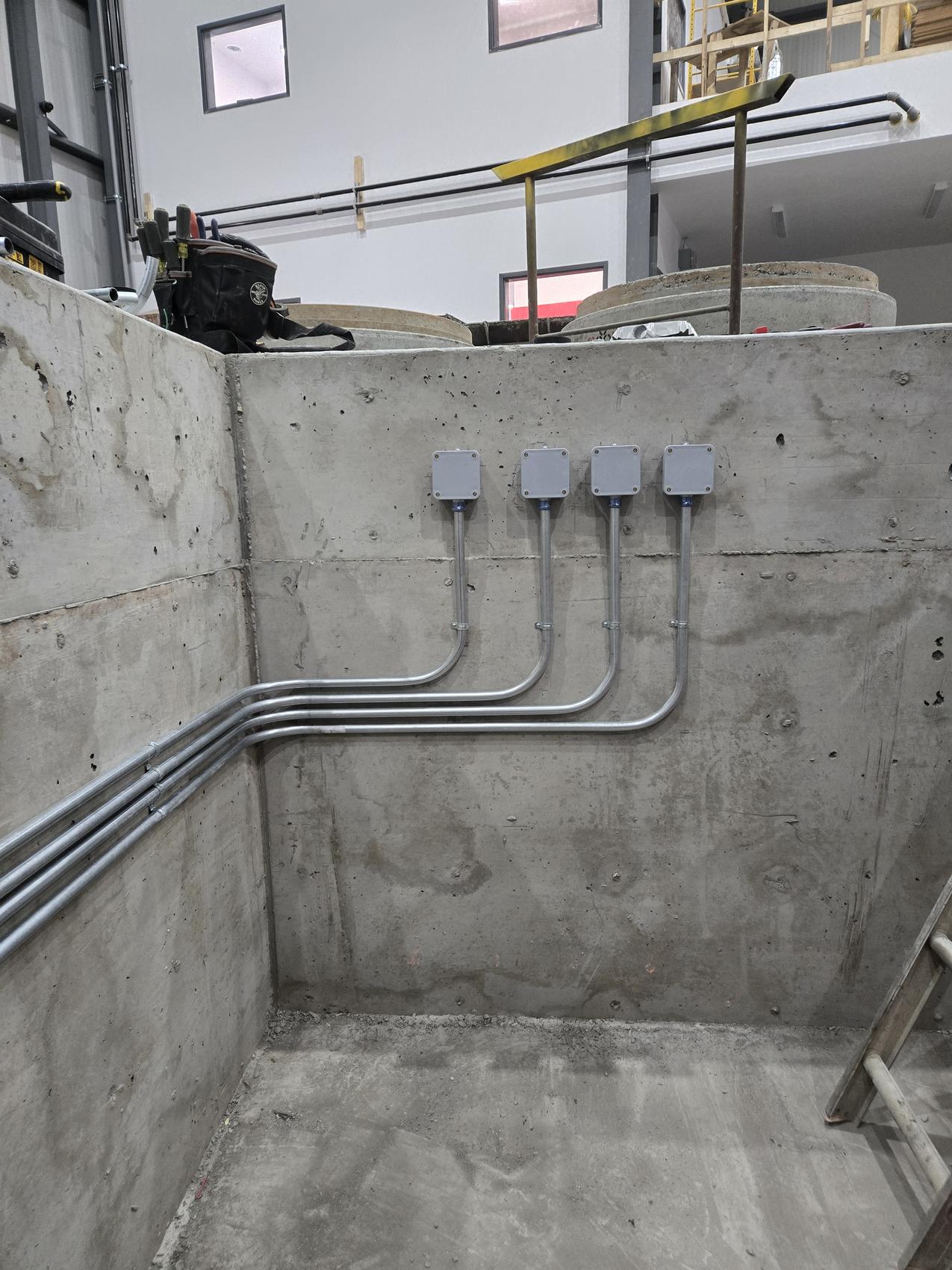Conduit runs and junction boxes on a concrete wall by Hi-Energy Electrical Services